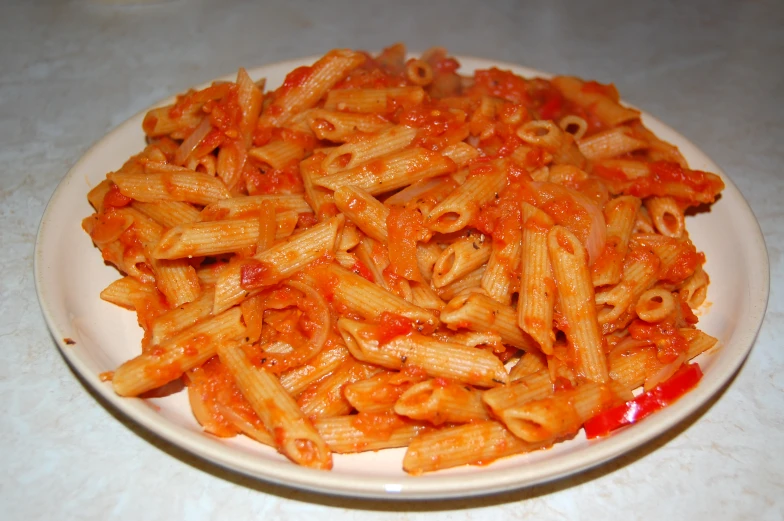 a plate with pasta that includes sauce and chili