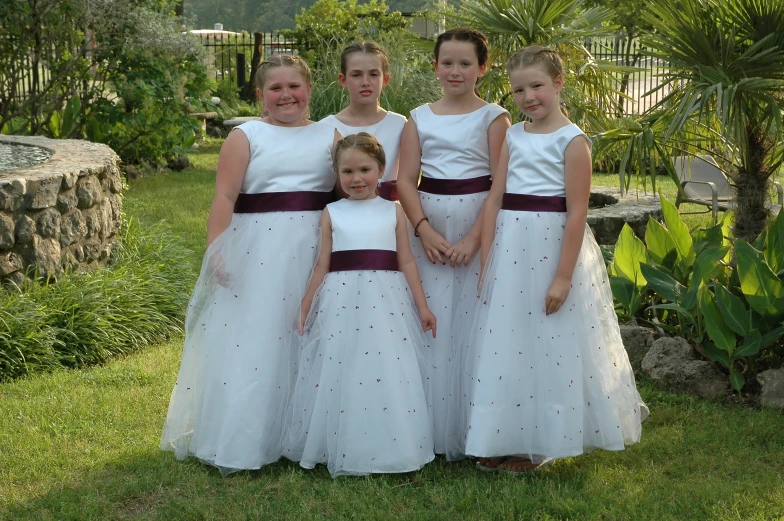 a group of girls dressed in white dresses