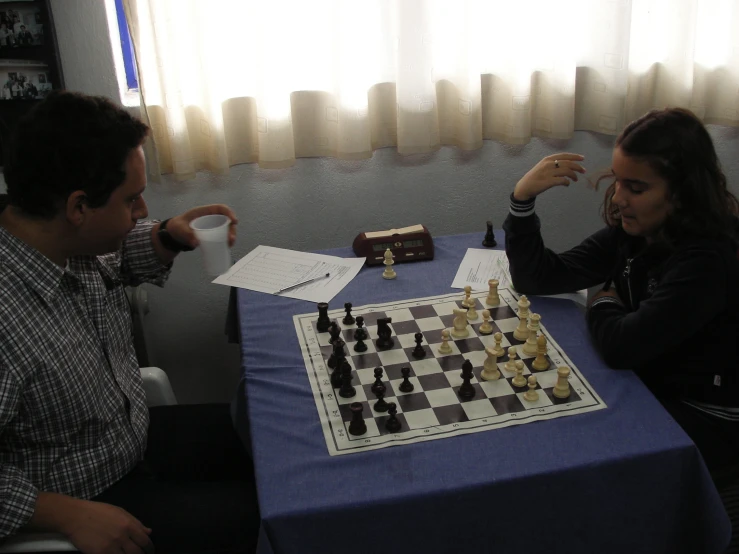 a man and woman playing chess together at a table