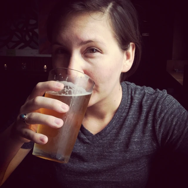 a woman is drinking a beer from the mug