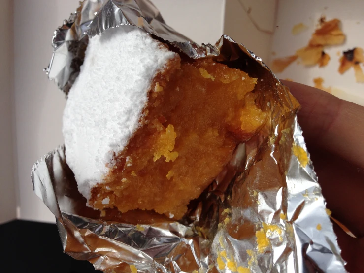 a person holding onto a piece of food in aluminum foil