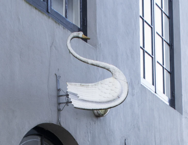 an odd looking swan statue on the side of a building