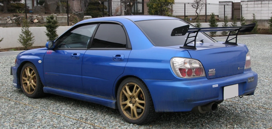 a blue sports car is parked with a box - springs and gold rims