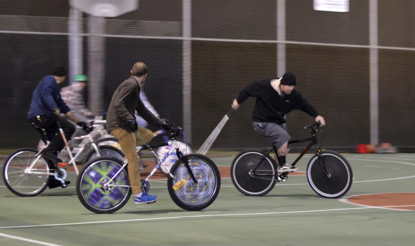 a group of people riding bikes in front of each other on a court