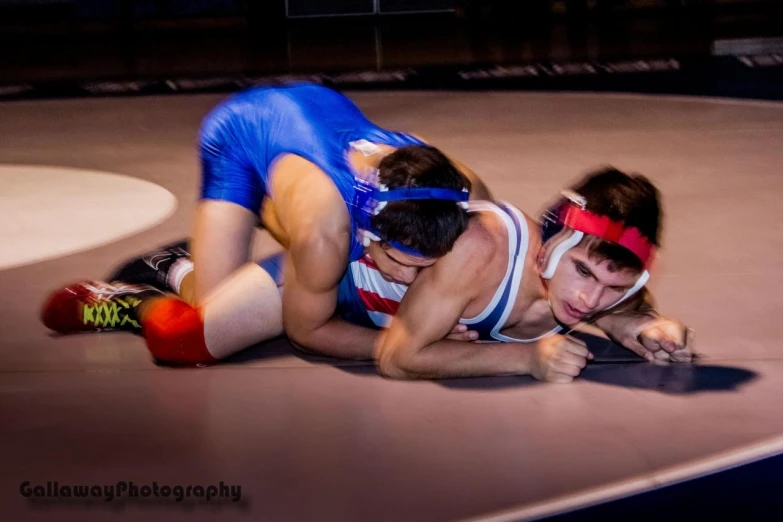 two wrestlers are wrestling on an indoor arena