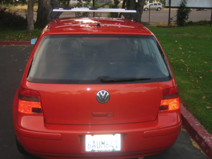 a red volkswagen parked in front of a park