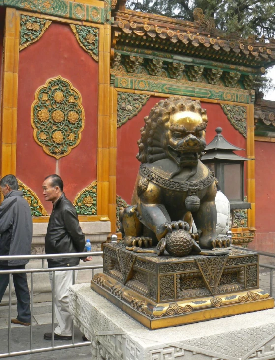 a statue of a golden lion sitting next to a tall building