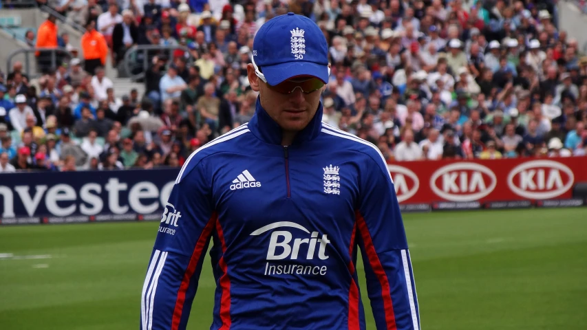 a man is walking across the field in a blue uniform