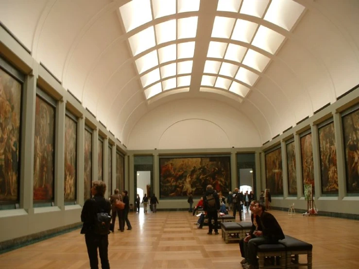 people standing in a long gallery with paintings on the wall