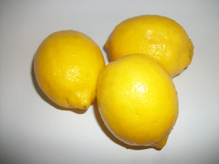 three lemons that are on a white table