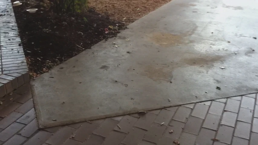 a concrete walkway is empty and wet and no one is seen