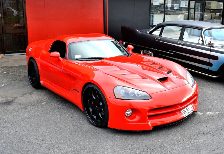 a red sports car is parked in front of two other cars