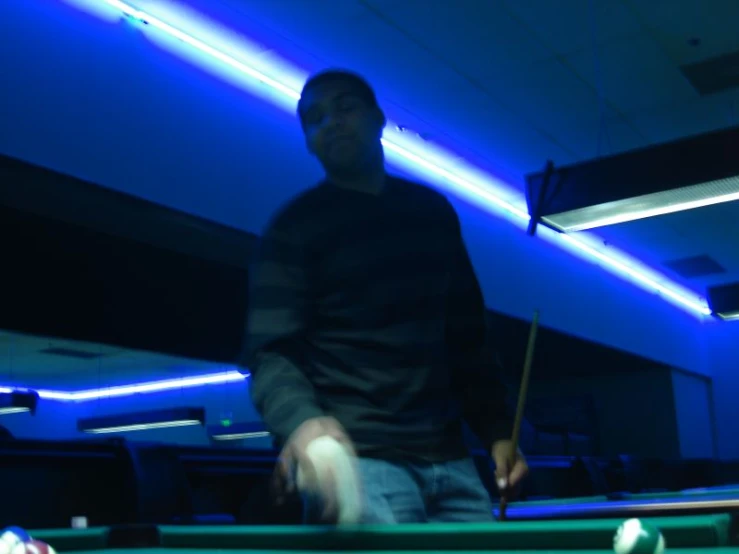 man playing pool at a night club with pool cues