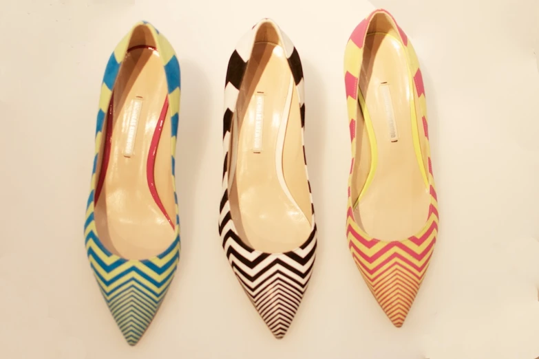 three colorful high heel pumps sitting on a counter