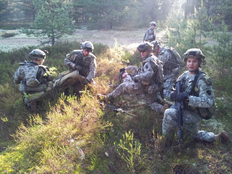 soldiers are gathered in a field and some are taking part in a simulated exercise