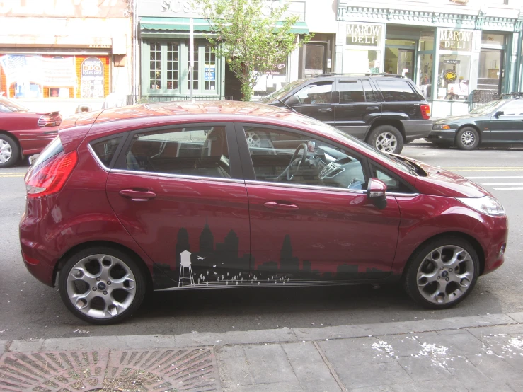 a small maroon car parked in the street