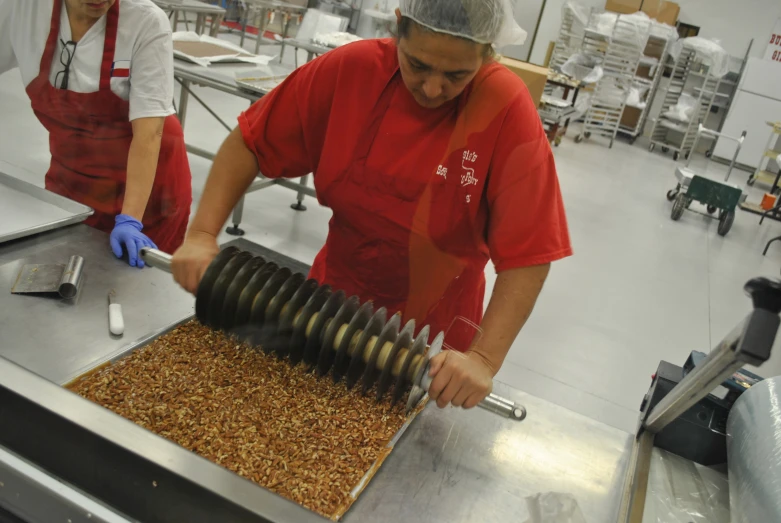 an employee in a kitchen pouring oil onto a container