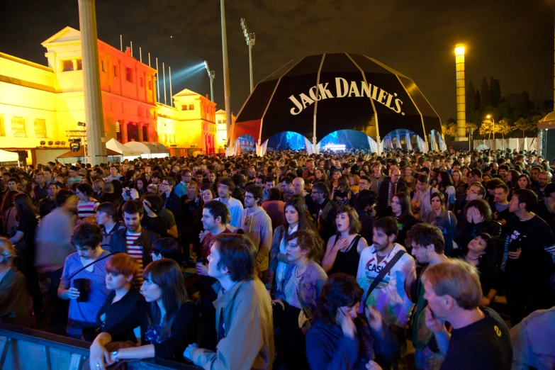 a crowd is gathered in a city square, with some performing on the stage