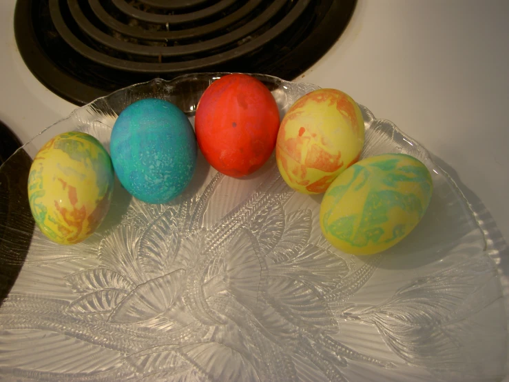 four decorated easter eggs sit in a bowl