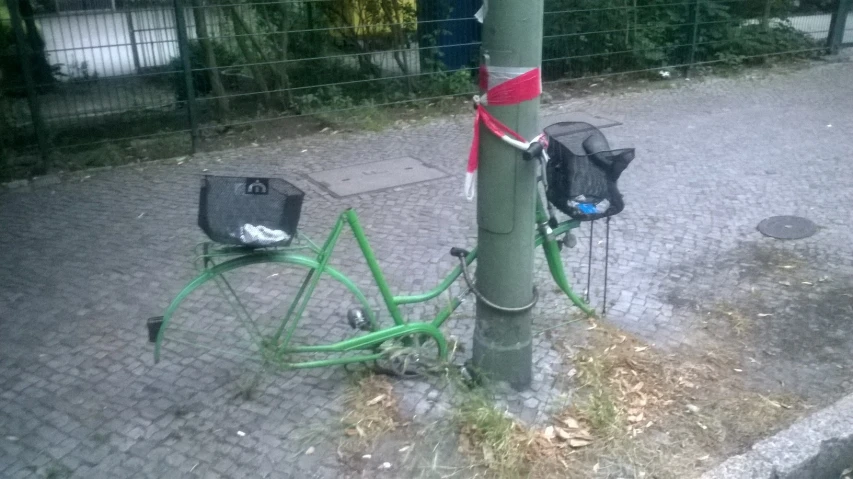 the bicycle is tied to the post and next to it is a basket bag