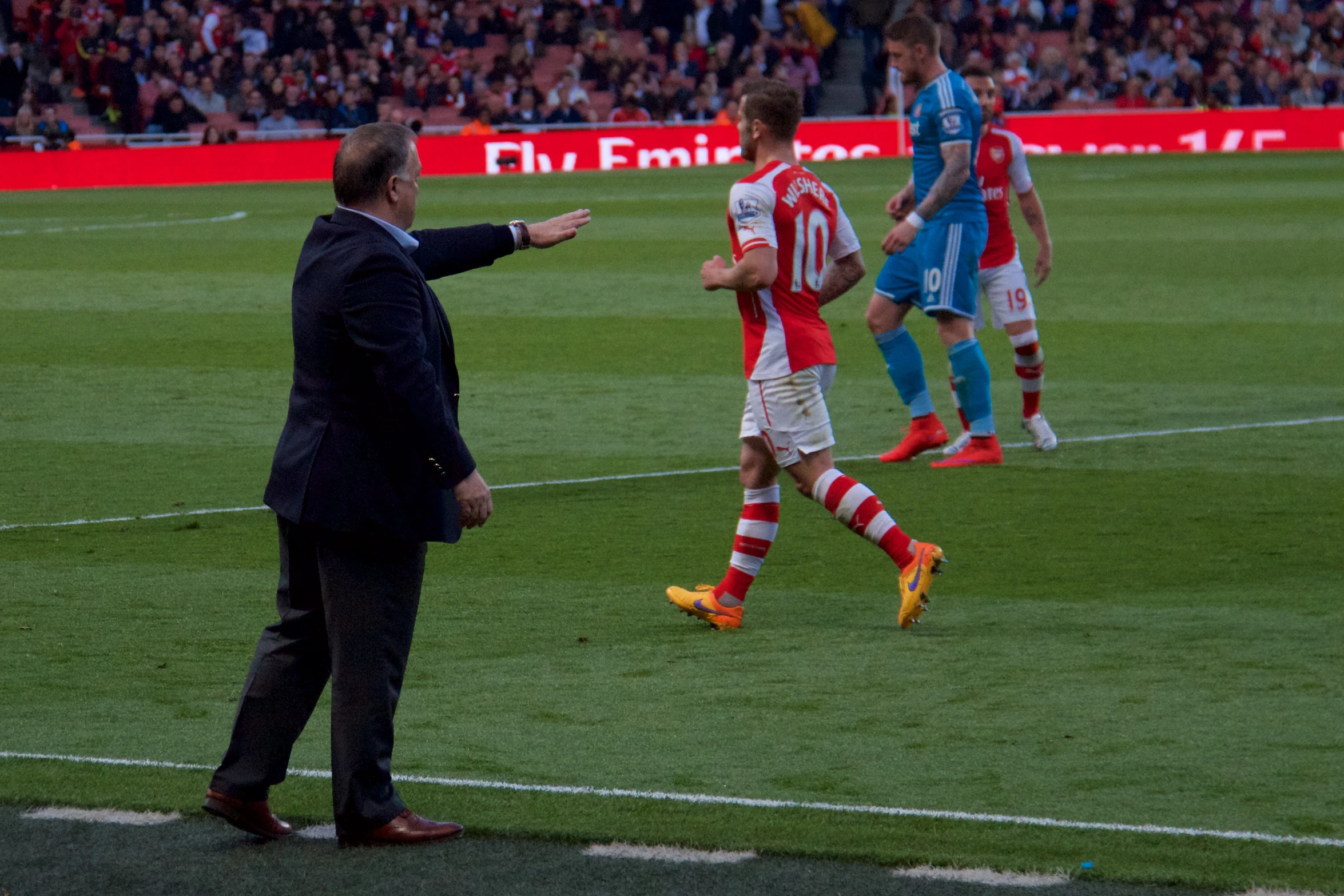 a coach is walking on the field and his team mates are watching