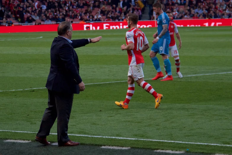 a coach is walking on the field and his team mates are watching