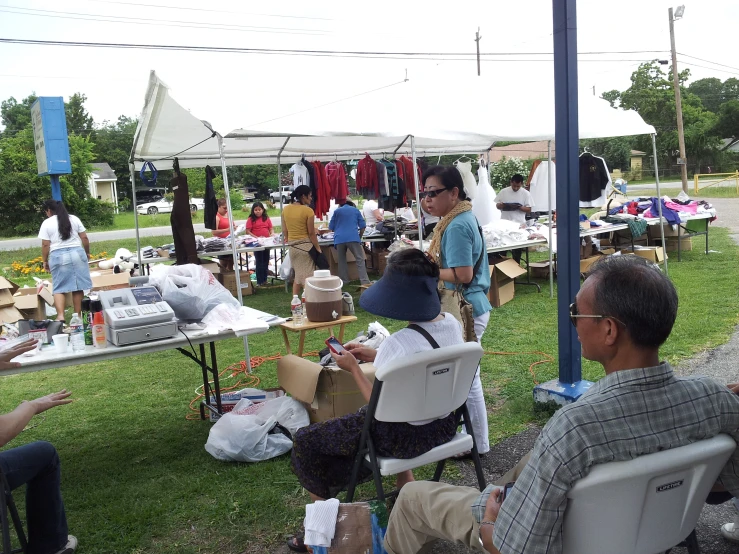 several people sitting on lawn chairs and tables at outdoor festival