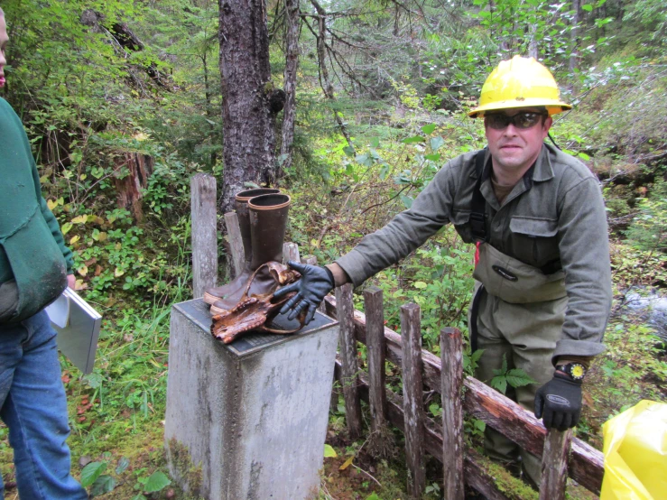 two men in hard hats standing next to an old box filled with logs