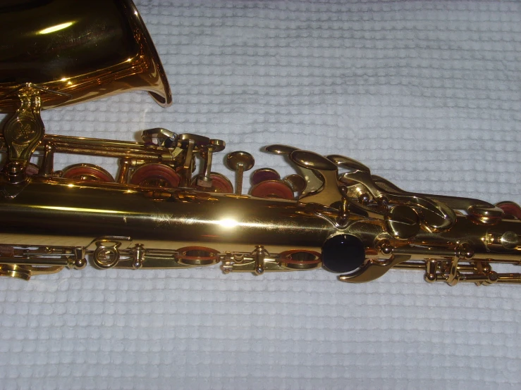 a close up of a ss saxophone sitting on a white sheet