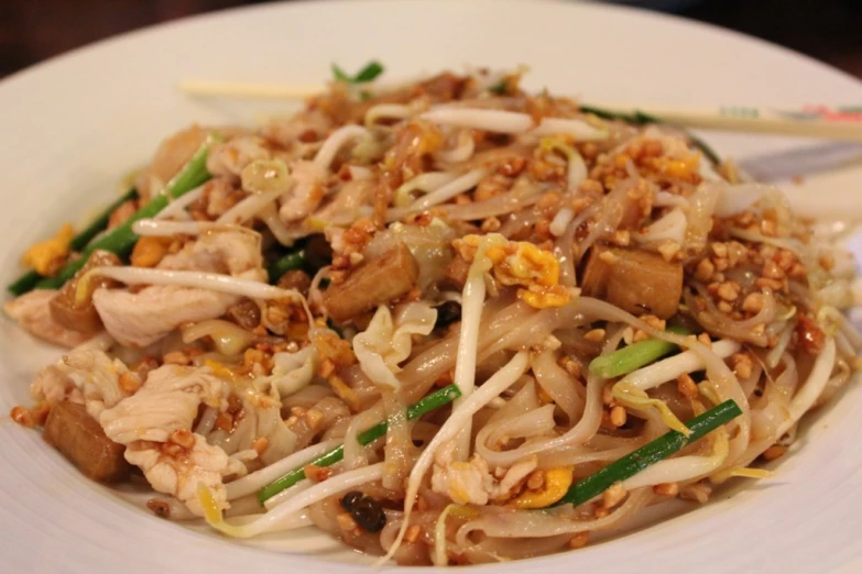 a white plate with noodles, meat, and other foods on it