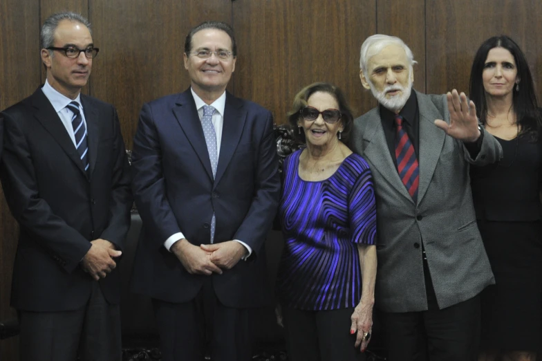 four people are standing in front of a wall in an office