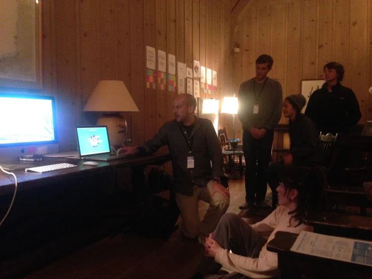 people gather around a large tv in the middle of a room