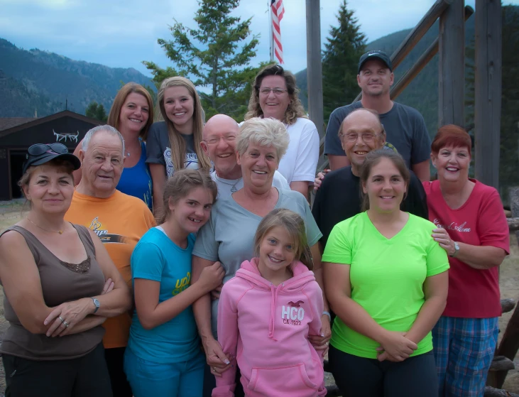 group of adults and children smiling on dirt with mountain in the background