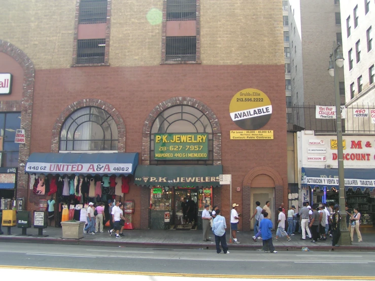 a row of shops with many people standing outside of it