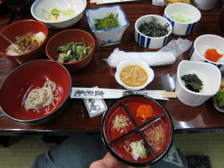 a person holding a spoon over several dishes