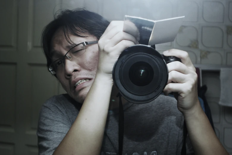 a young man holds up a camera while looking at his digital device