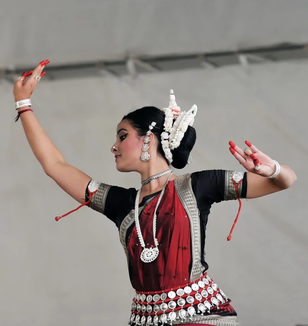 a woman wearing a red and black outfit holds up her hands