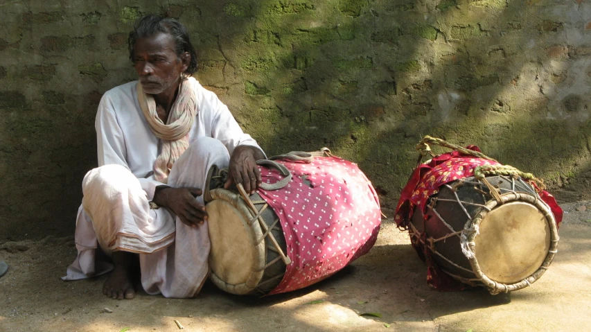 a man sitting on the ground next to two drums