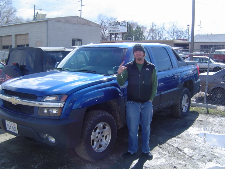 a man posing in front of his pickup truck