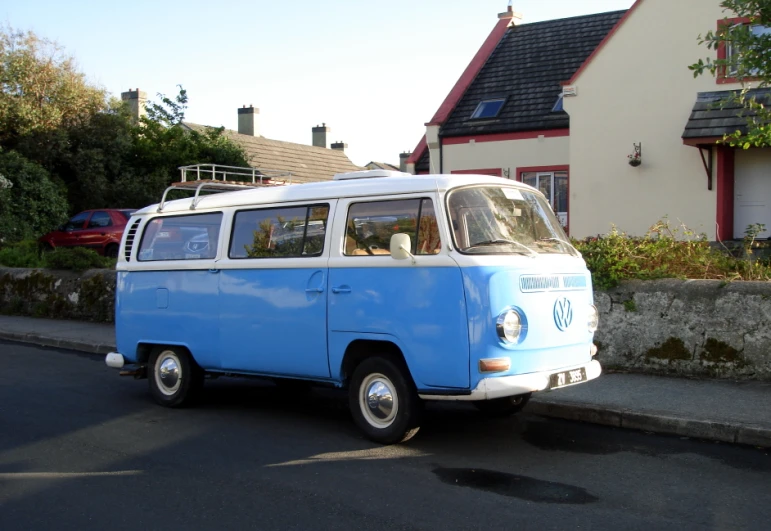 an old blue and white bus traveling down a road