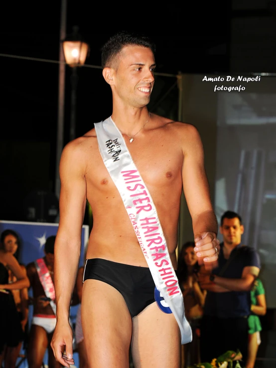 the man is walking down the runway with a miss america sash