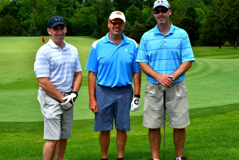 three men standing next to each other on top of a golf course