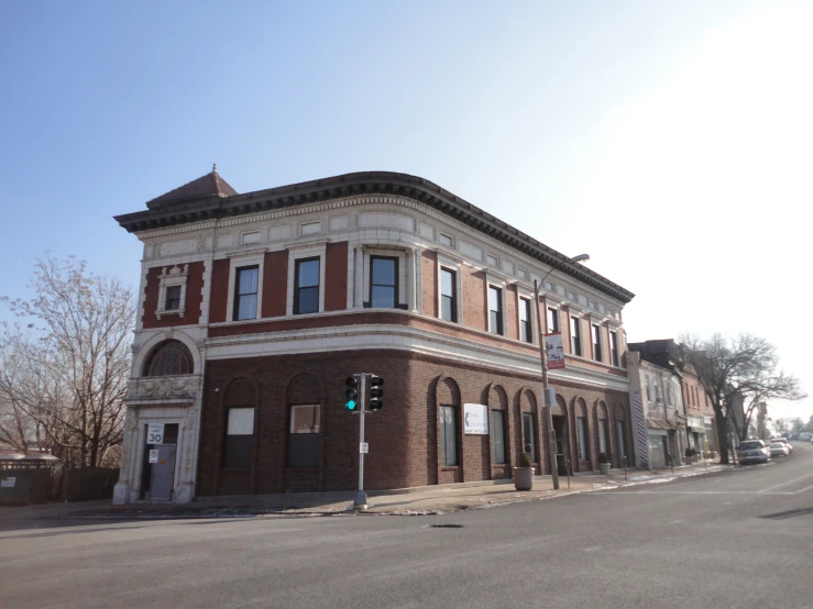 an old stone building sits in the middle of a small intersection