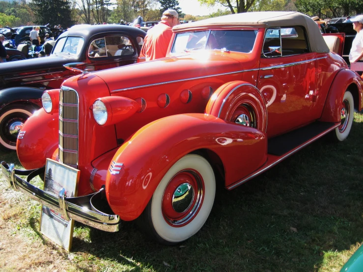 the front of a red classic car parked in the grass