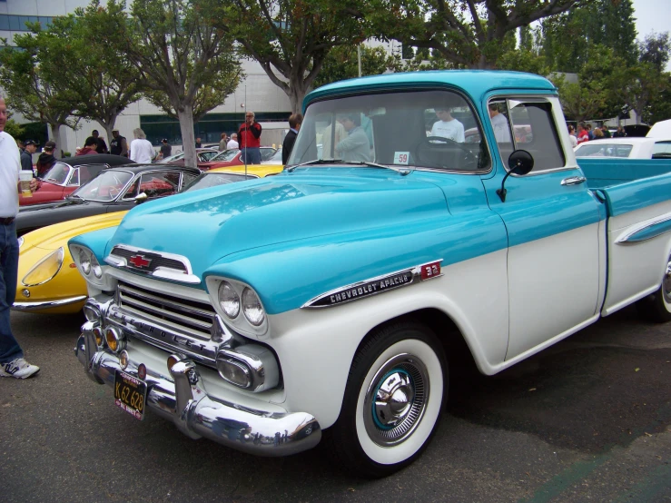 a classic turquoise and white truck at a car show