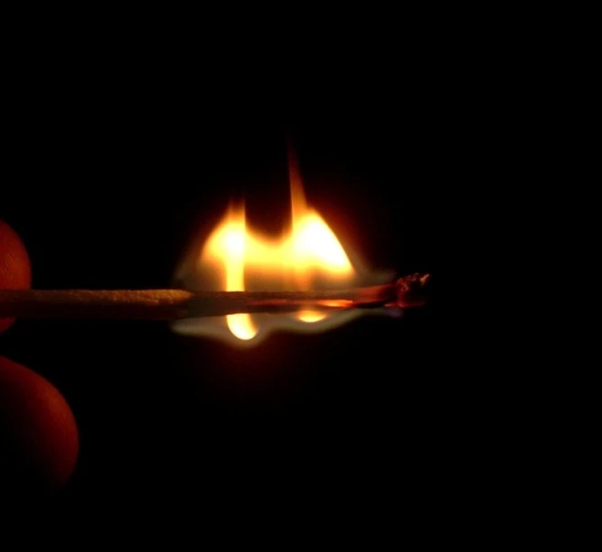 a match with an orange lit flame on a matches stick