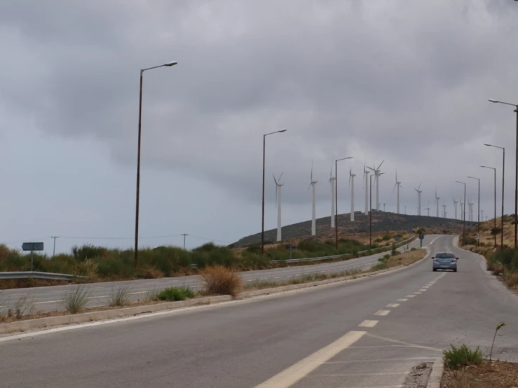 cars driving on a highway lined with wind generators