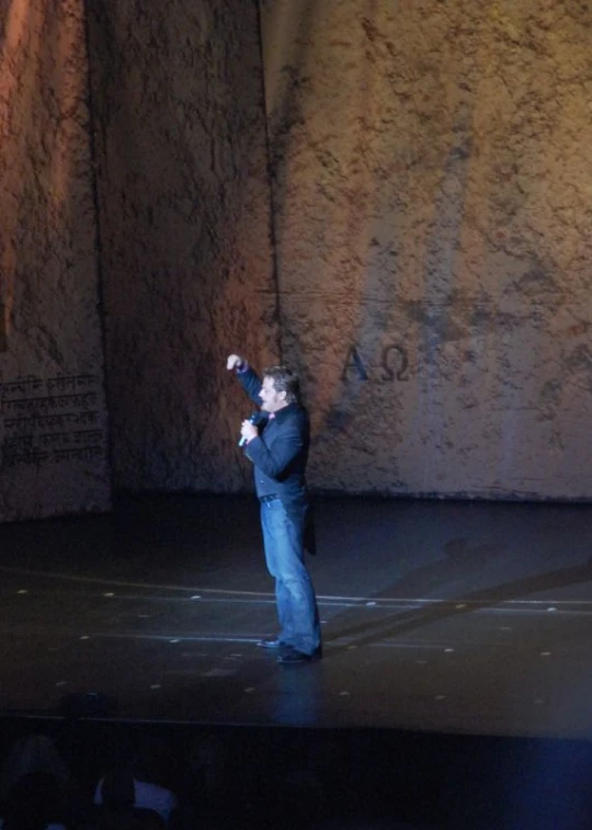 a man in blue standing on a stage with his arms raised