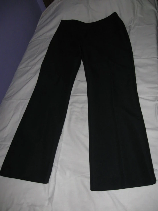 a pair of black pants lay down on a bed