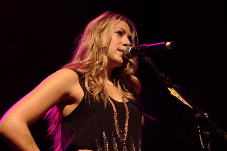 a woman standing in front of a microphone and wearing a black tank top